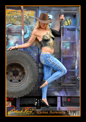 blonde woman body painted with a detailed black and gold top and detailed jeans.